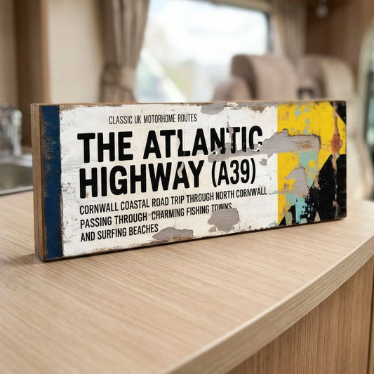 A rectangular vintage-style road sign on 18mm MDF for The Atlantic Highway A39. Features black text on a white background with a blue stripe, yellow arrow, and heavy integrated faux-rust and weathered paint effects.