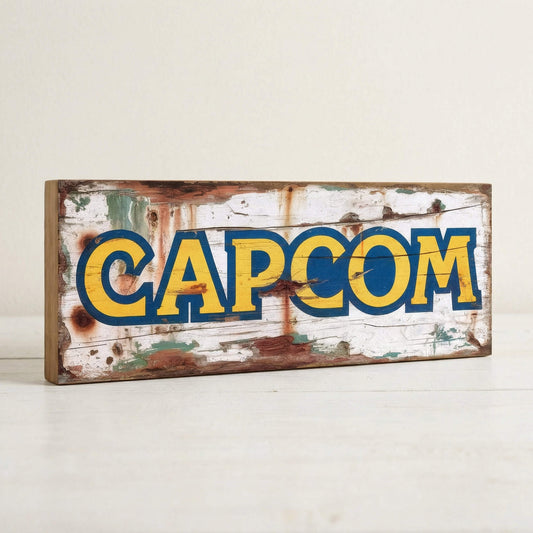 Capcom retro gaming logo vintage wooden sign handmade on 18mm MDF with bold yellow and blue lettering on heavily distressed white background, freestanding on light surface