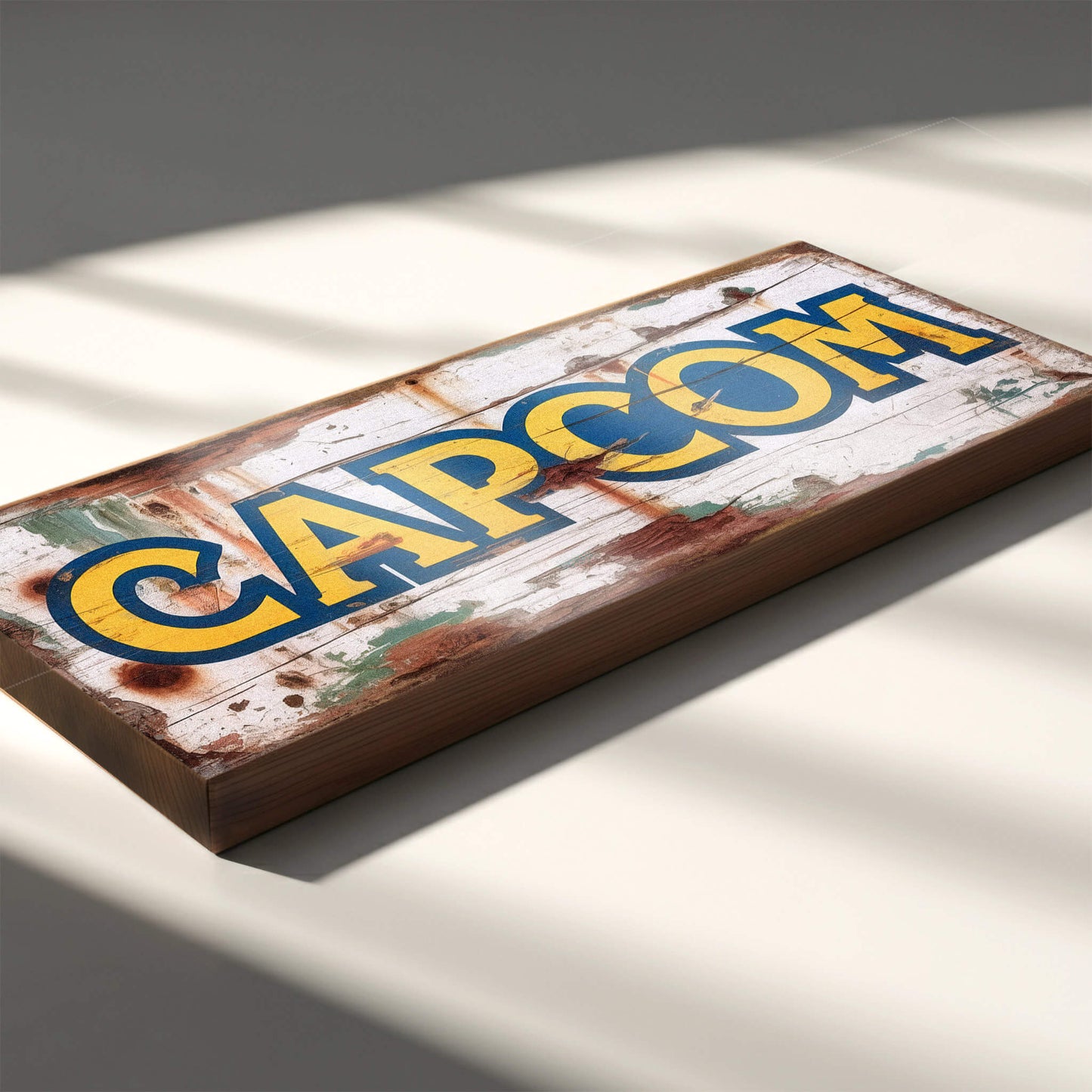 Capcom retro gaming logo vintage wooden sign handmade on 18mm MDF with bold yellow and blue lettering on heavily distressed white background, freestanding on light surface