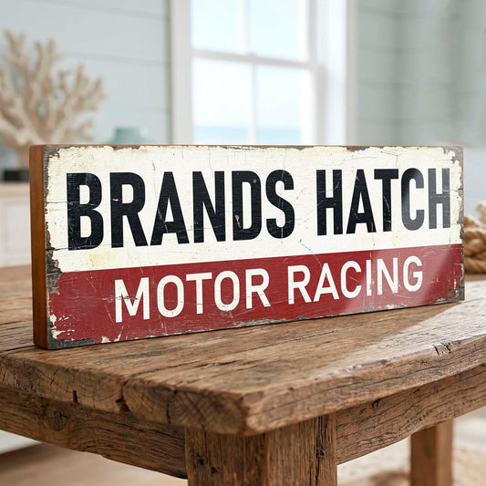 Close-up photograph of a handmade, vintage-style wooden wood sign reading "BRANDS HATCH MOTOR RACING" in classic black and white lettering on a weathered maroon and off-white background with distressed edges.