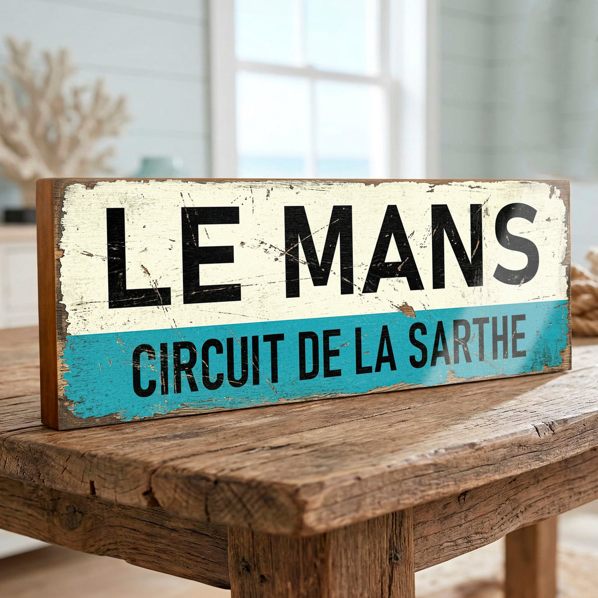 Rectangular vintage style Le Mans Circuit de la Sarthe sign with distressed cream and turquoise blue graphic on 18mm MDF, freestanding on a rustic wooden table