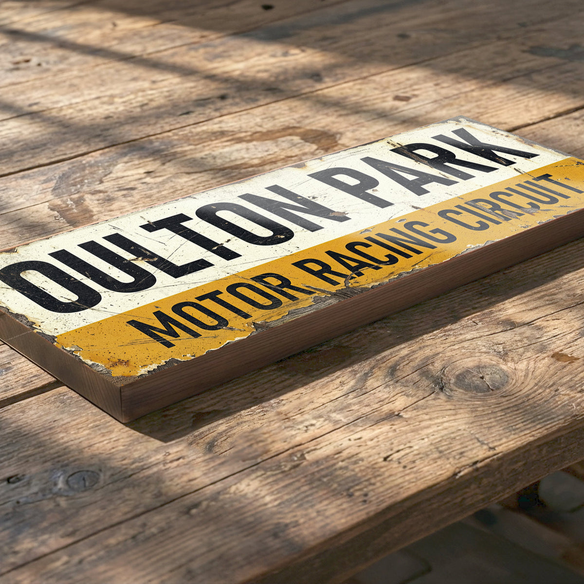 A rustic rectangular wooden sign reading "Oulton Park Motor Racing Circuit" in black lettering, with a distressed cream top half and a yellow bottom strip, photographed on a weathered wooden surface.