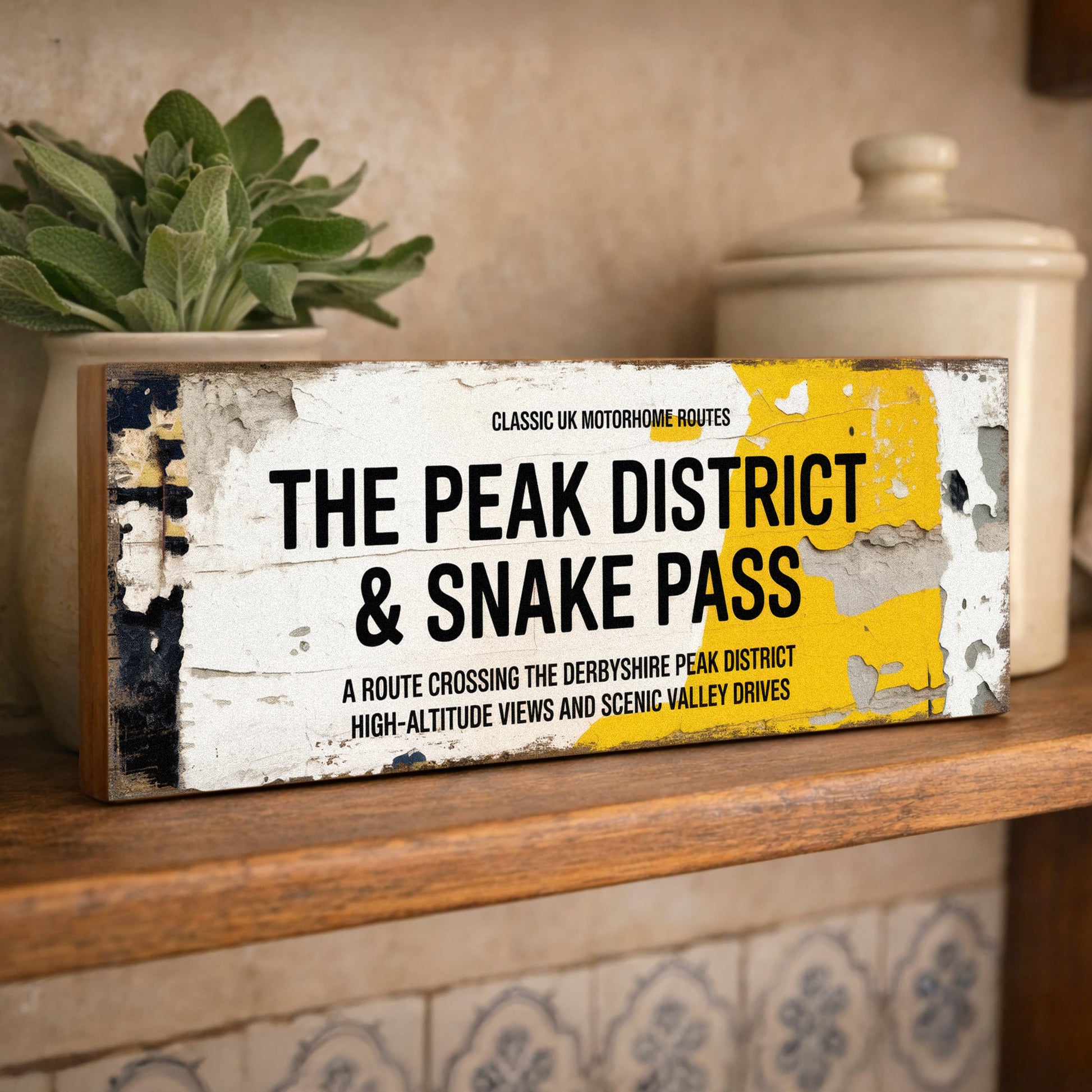 Rectangular vintage road sign for The Peak District and Snake Pass featuring high-altitude view details with a weathered retro aesthetic.